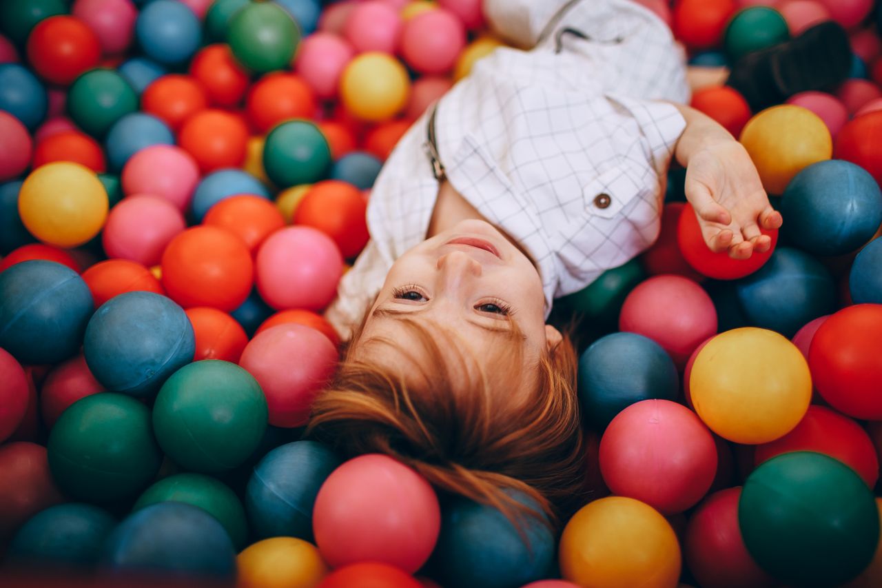 our-mission Adorable child enjoying playtime in a vibrant, indoor ball pit.
