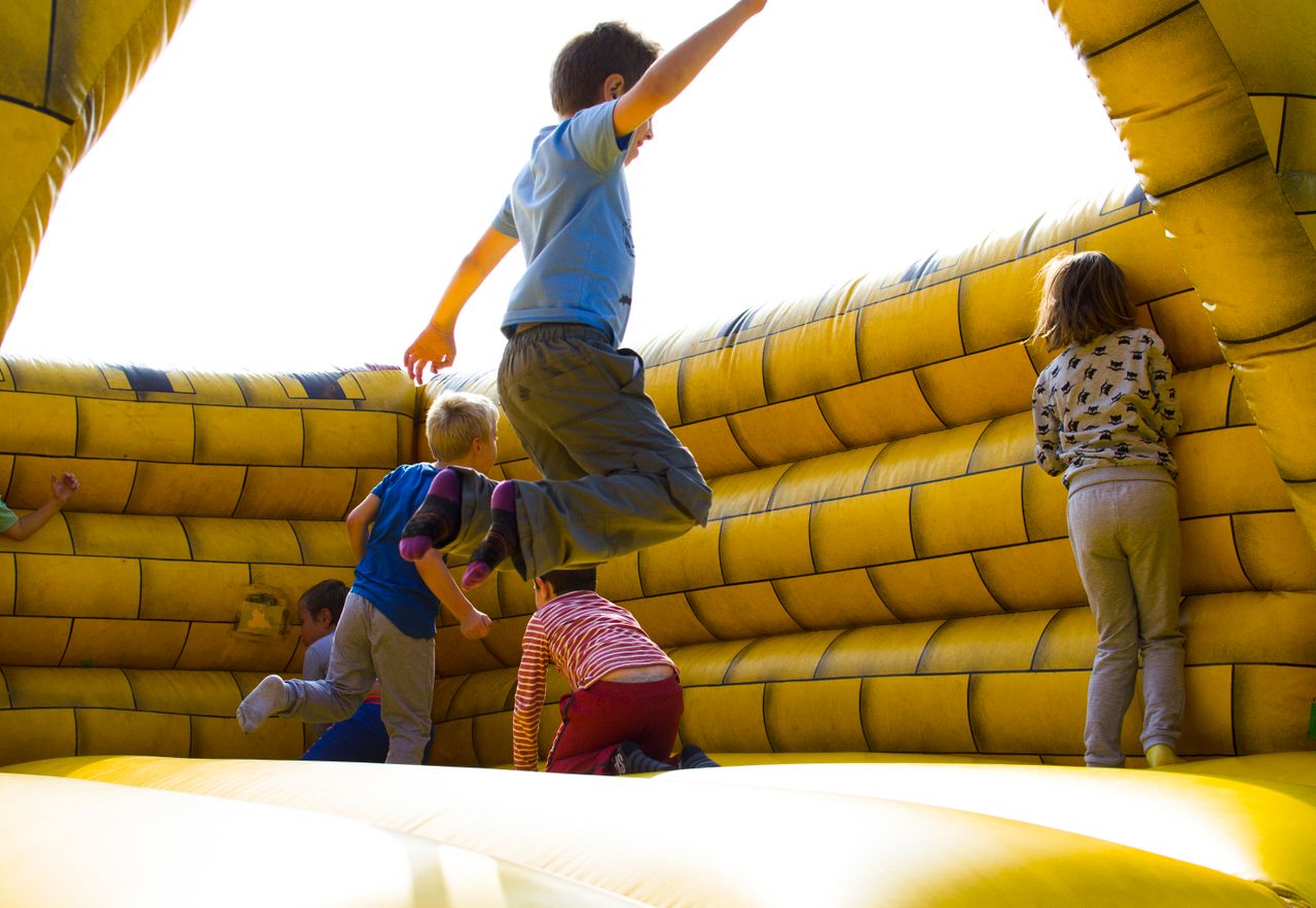 service-01 Kids enjoying a fun time bouncing in a vibrant inflatable castle outdoors.